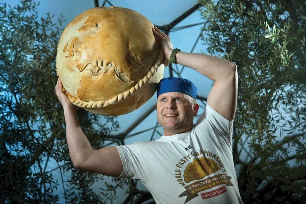 A man holding a large round pasty. 