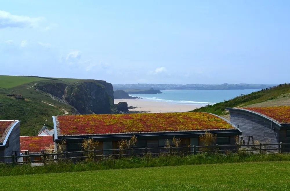 A building with a mossy roof and a beach in the background. 