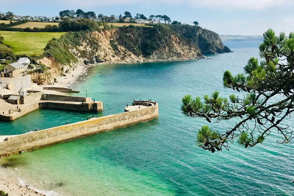 Small beach and harbour with a stone wall.