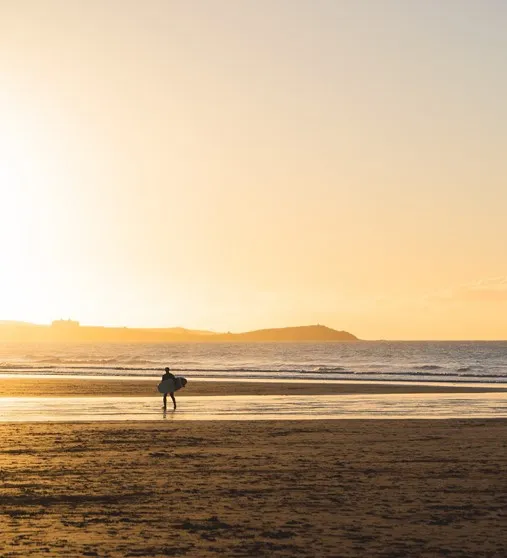 A person holding a surfboard on a beach.