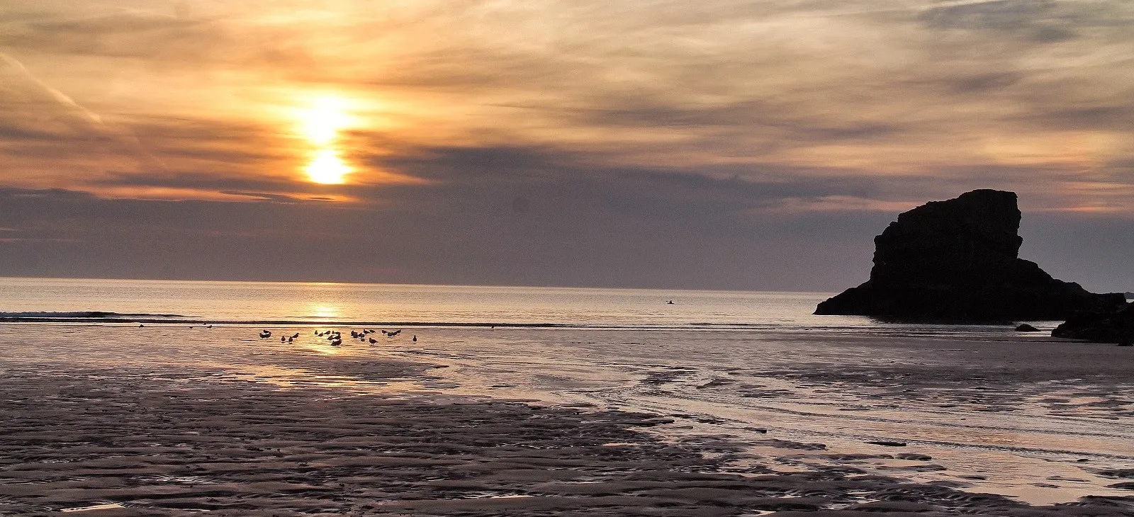 Sunset over the beach at low tide.