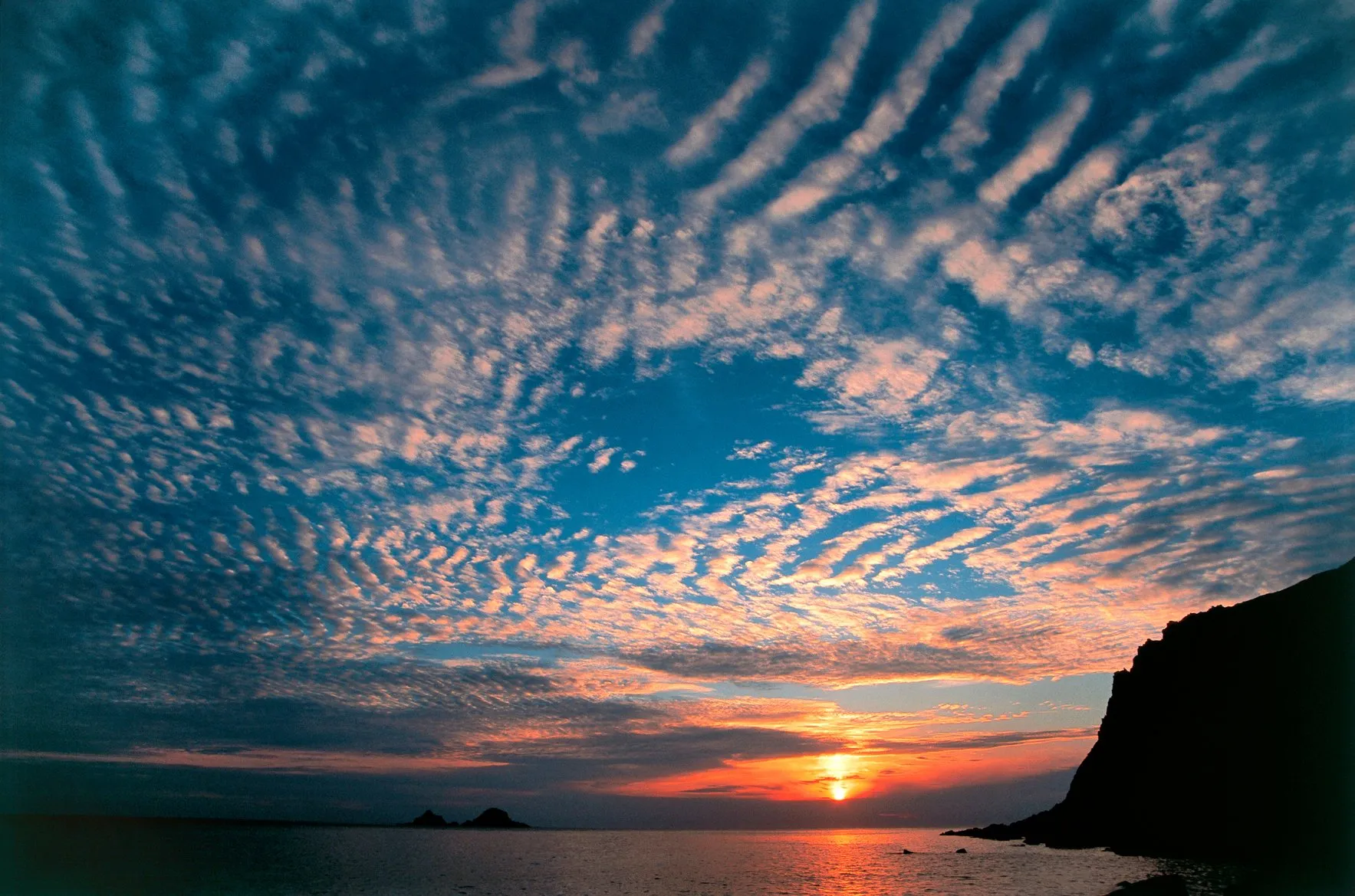 An image of a sunset over the sea with 'mackerel sky' clouds