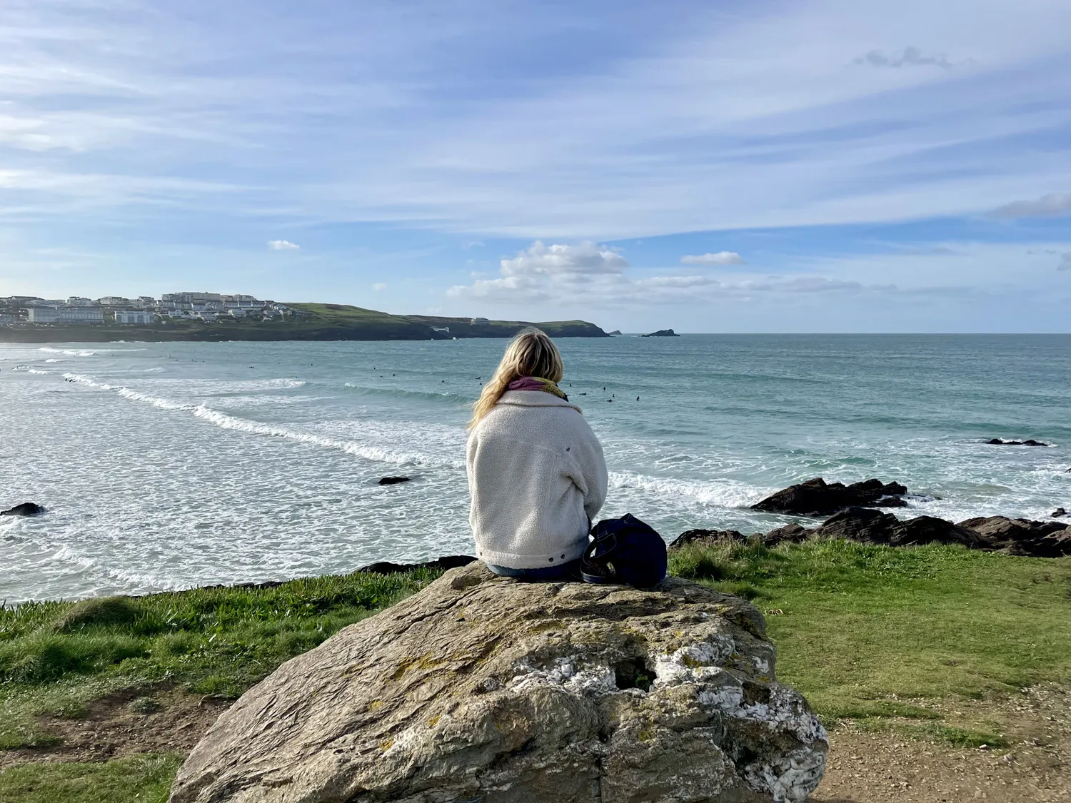 Woman sat on rock overlooking Fistral Beach
